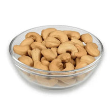 Whole unsalted cashews in a clear glass bowl, light beige kernels