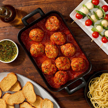 Beef and pork meatballs in marinara sauce served in a black baking dish