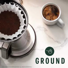 Ground coffee in open stainless grinder, dark coffee grounds