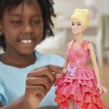 Fashion doll holding a pink ruffled dress piece