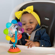 Baby in denim outfit playing with light-up rainbow spinning tray suction toy