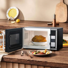 Microwave oven with door open, warming food in a glass dish on countertop