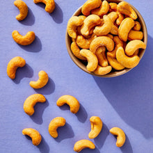 Roasted salted cashews in a bowl with cashew pieces scattered