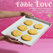 Pink nonstick baking sheet holding seven cookies, carbon steel cookie pan set
