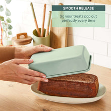 Mint green ceramic nonstick loaf pan with sliced cake on a plate