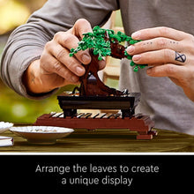 LEGO Icons bonsai tree set hands installing green leaves on the brown trunk