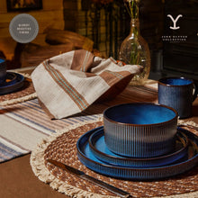 Blue ceramic dinnerware set with stacked plates and ribbed cups on a table