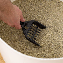 Hand using black litter scoop in a white enclosed cat litter box