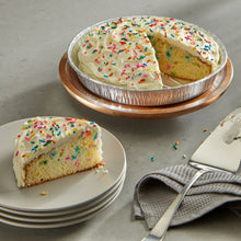 Round silver foil cake pan with frosted cake on plate and sliced pieces