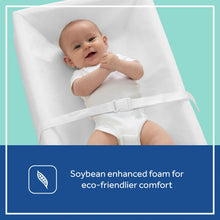 White changing pad with a baby secured by its adjustable restraint strap