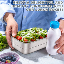 Stainless steel lunch box with compartment filled with salad, held while opening