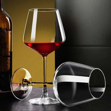 Single red wine glass with burgundy wine, clear stem and round base on table