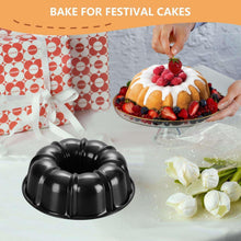 Black bundt cake pan with a decorated fruit cake on top.