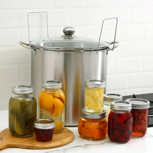 Water bath canner pot with lid next to filled canning jars on a board