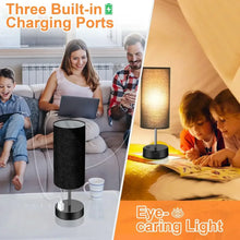 Table lamp with black cylindrical shade and base, glowing warm light on a stand.