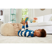 Baby lying on a couch holding a Bluey ring phone toy with orange and blue buttons