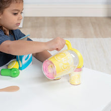 Pretend lemonade toy pitcher tipped to pour yellow drink into cup, with green scoop nearby