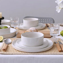 White stoneware dinnerware set with stacked bowls and plates on a table
