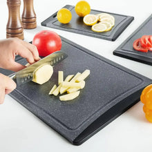 Dark grey cutting board with speckled surface while cutting vegetables.