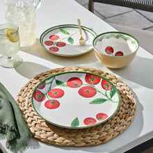 Tomato-pattern round plates and bowl with green trim, beige bowl on table