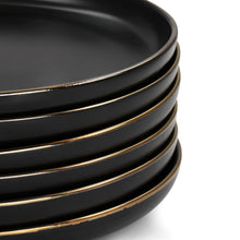Stacked black stoneware dinner plates with thin gold rim line, side view