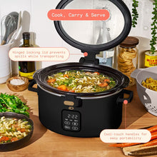 Black digital slow cooker with its hinged lid open, showing soup inside and side handles