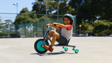Teal mini 3-wheel tricycle with black seat on pavement during a ride