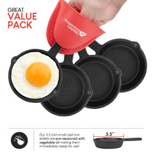 Set of black mini cast iron skillets with a red silicone mitt, holding a fried egg