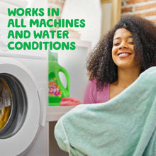 Gain Happy liquid laundry detergent jug beside washing machine with folded laundry