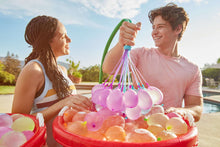 Inflating self-sealing water balloon cluster with pastel pink balloons and green hose