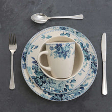 Floral dinnerware: blue rose plate with white cup and saucer, plus utensils