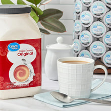 Coffee creamer bottle beside a white mug with latte-style swirl and spoon
