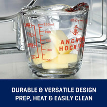Clear glass measuring cup with handle and red measurement markings, filled with milk