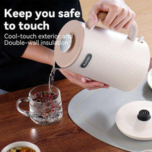Cream electric kettle pouring water from spout, with cool-touch handle
