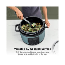 Sage leaf green Ninja pressure cooker with sautéed vegetables in pot, open lid