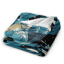 Folded flannel throw blanket with blue turtle character in teal-and-black splash design