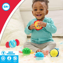 Toddler playing with colorful sensory balls: lion, green turtle, and blue shell