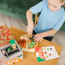 Wooden pizza board with removable toppings pieces arranged by hands