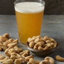 Whole cashews in a small bowl with scattered nuts on a table