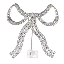 Silver jeweled bow tree topper with an attached battery pack, lights off