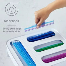 White food bag dispenser with wide slots and colored bag rolls; hand grabs a roll