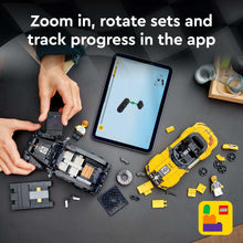 Disassembled LEGO car parts with minifigures beside a tablet device