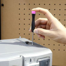 Hand holding a black and pink utility tool with a pointed tip near a tool box