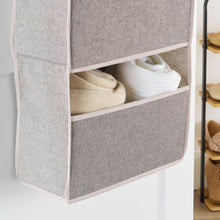 Gray fabric storage shelf with open cubbies holding folded items