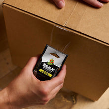 Clear packing tape dispenser held in hand over a cardboard box