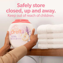 Dreft baby laundry detergent jug placed out of reach near folded towels and hands.