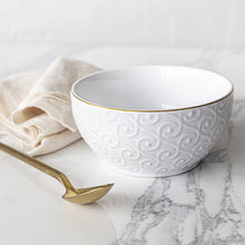 White stoneware bowl with embossed swirl texture and gold rim