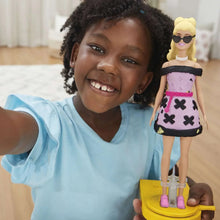 Girl holding a fashion doll in a pink skirt with black heart trim