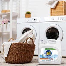 Liquid laundry detergent jug and cap near folded laundry by a washer