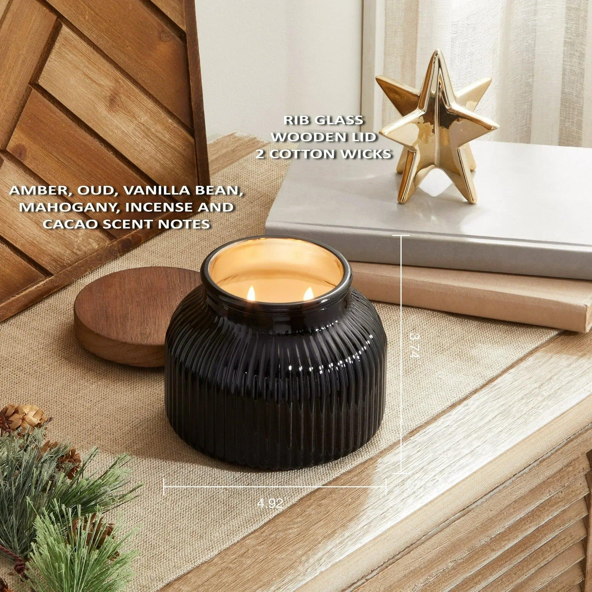 Black ribbed glass jar candle with wooden lid, lit